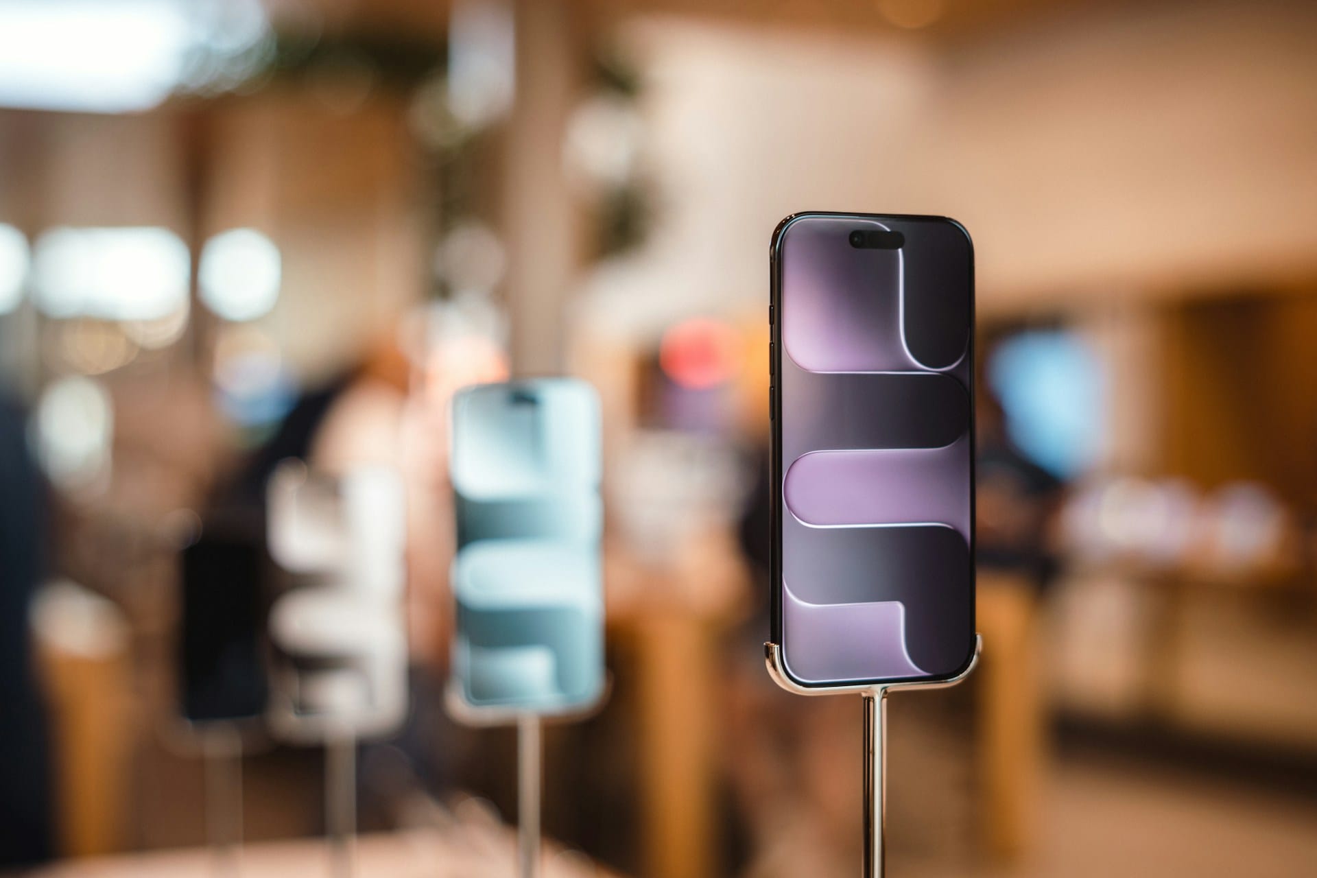 Rows of smartphones with lit screens on retail display stands